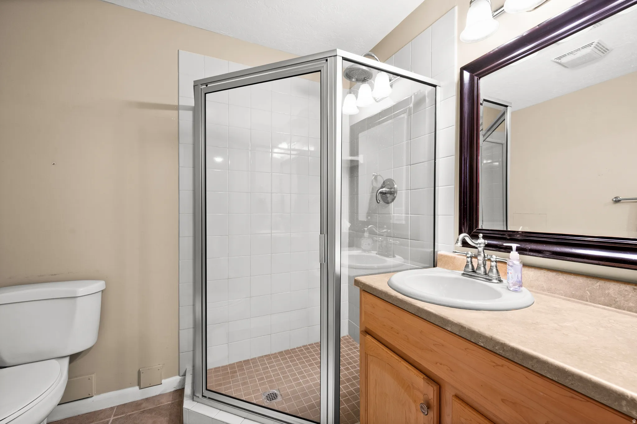 Bathroom featuring a glass-enclosed shower with white tiled walls and a tiled floor
