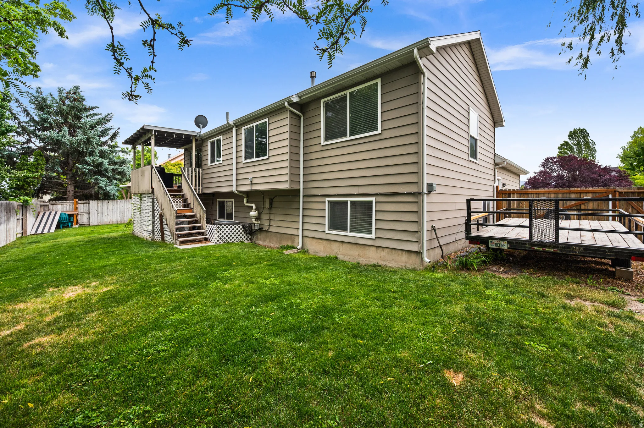 Spacious rear yard featuring an expansive lawn, a multi-level deck with staircase, and a wood-slat fence