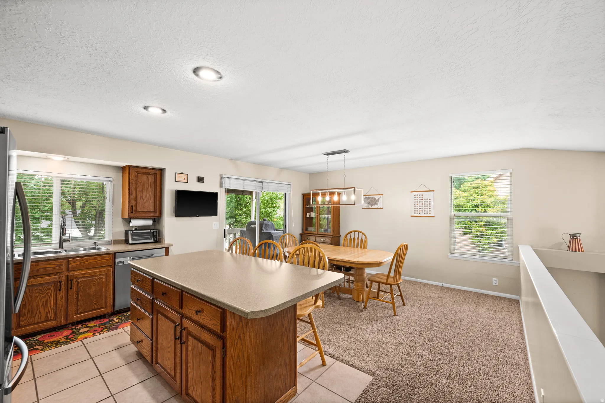 Open-concept kitchen and dining area featuring wood cabinetry, a central island with integrated seating, and a sliding glass door providing exterior access
