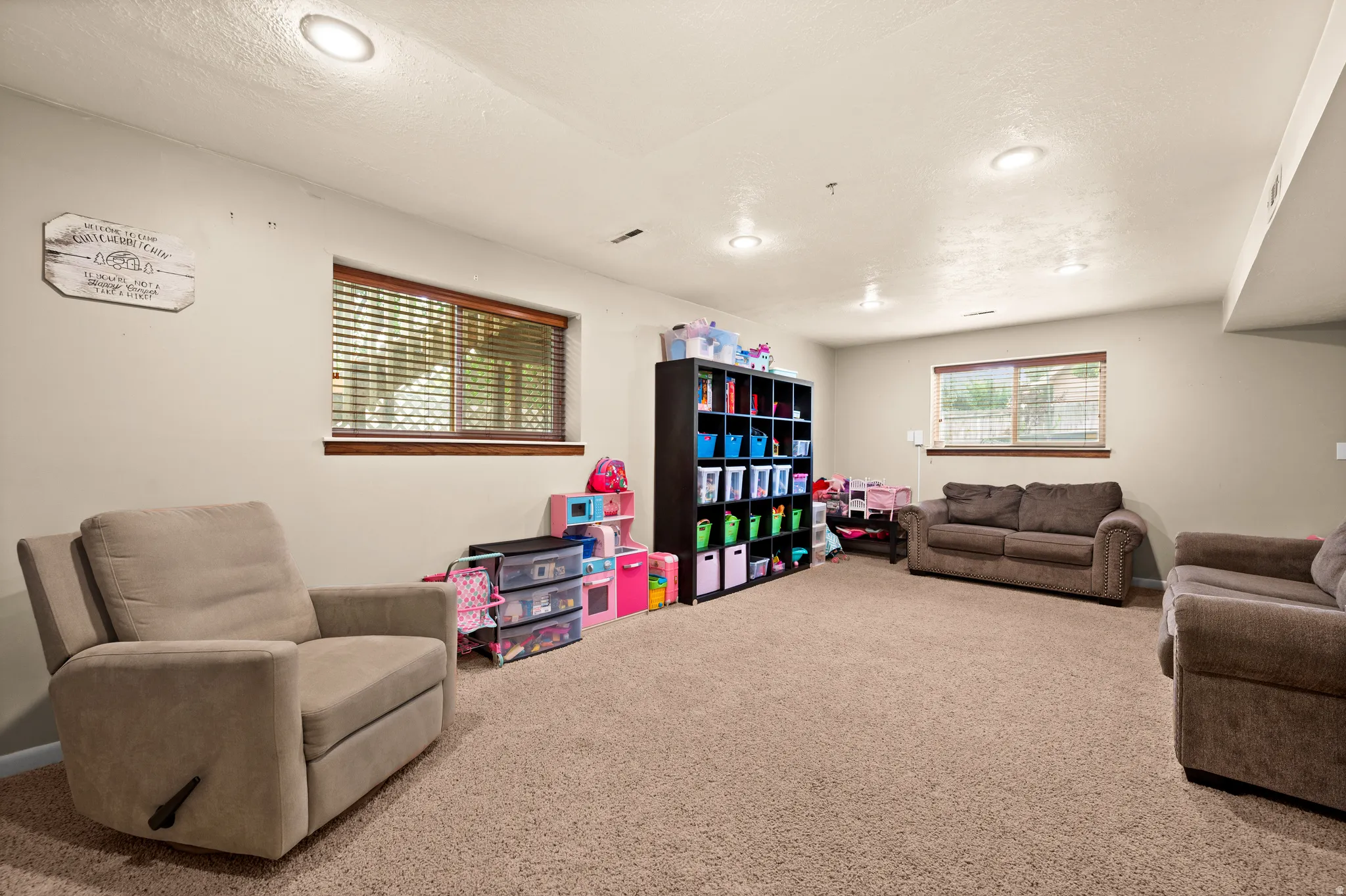 Spacious room featuring neutral carpeting, recessed lighting, and multiple windows with wood-finish trim