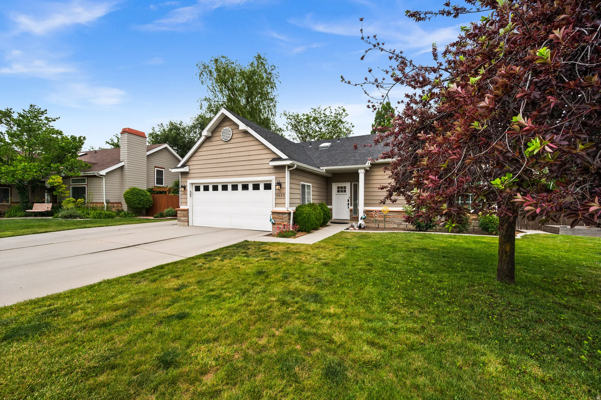 Siding exterior with stone accents, a two-car garage, and a covered entry