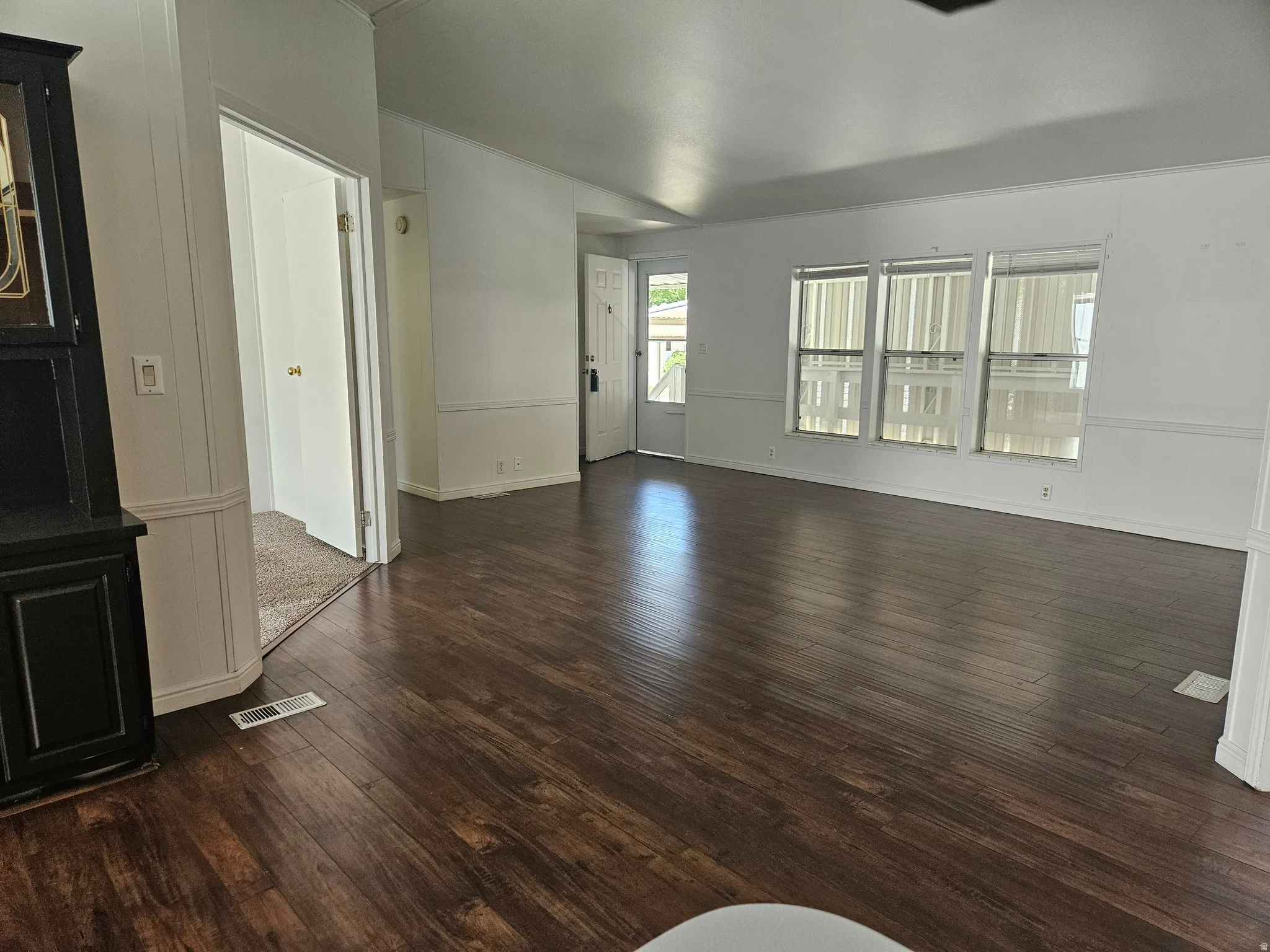 Spacious interior featuring wood-finish flooring, white walls, and wainscoting