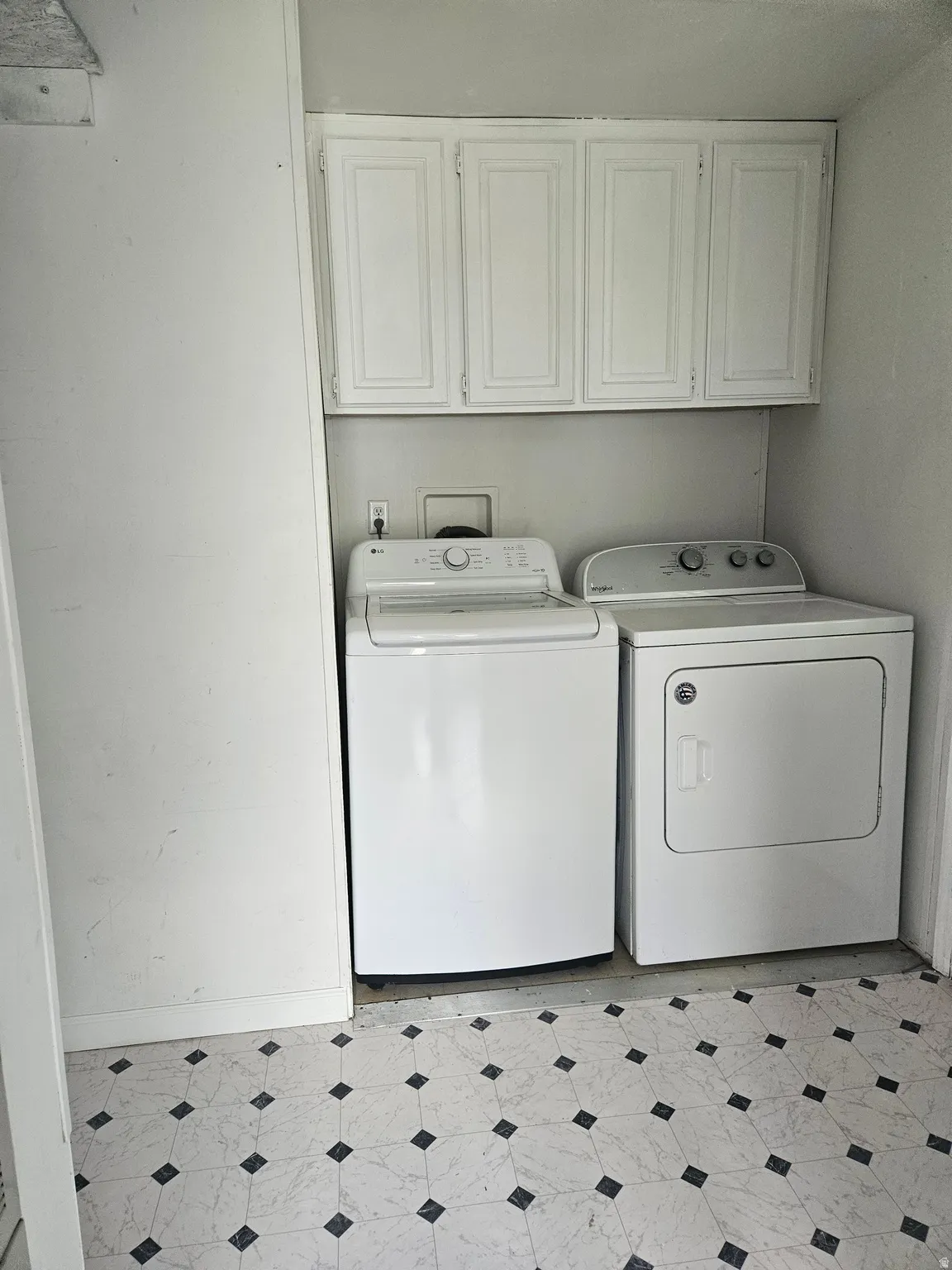 Dedicated laundry space featuring overhead white cabinetry for storage