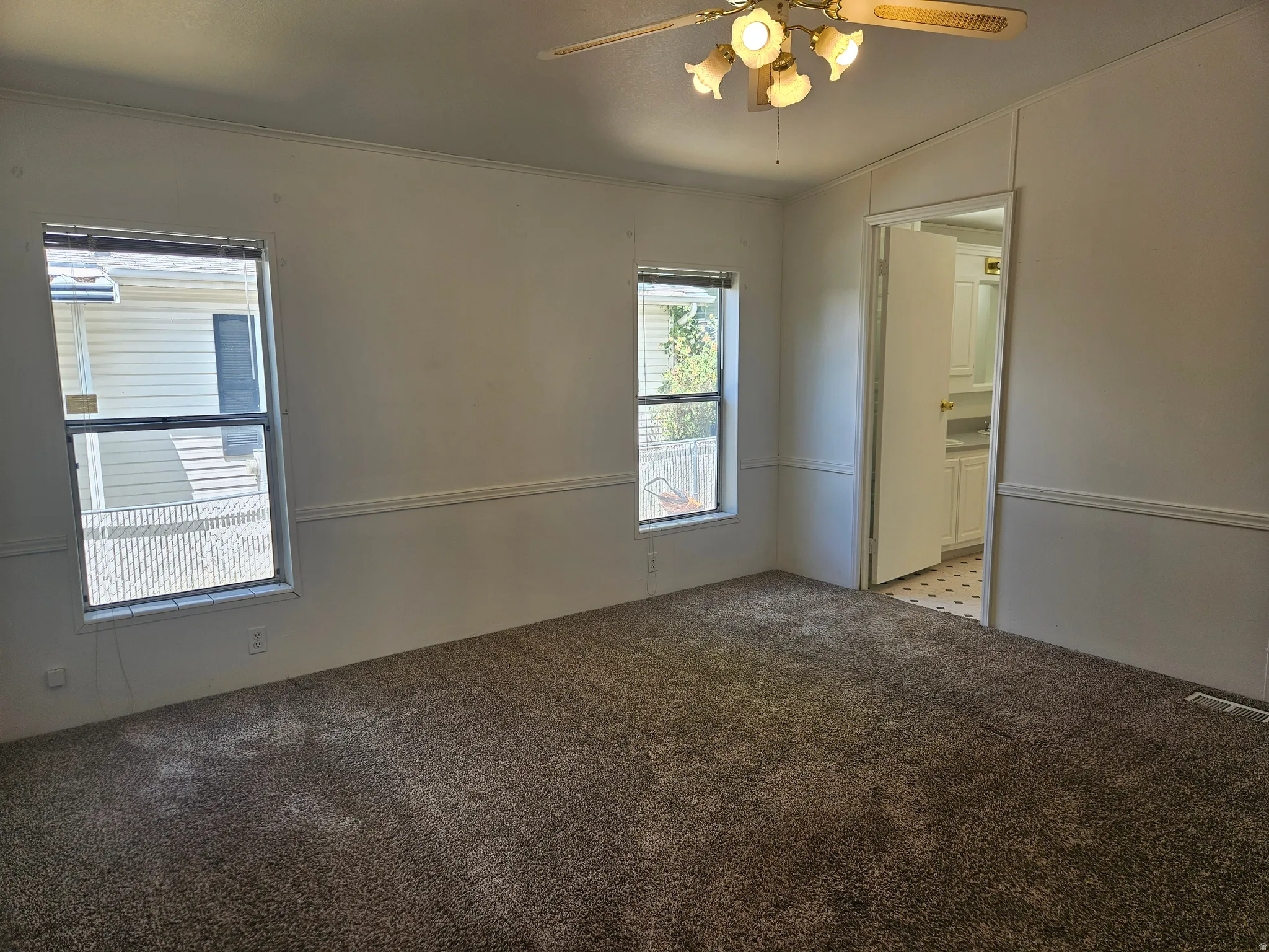 Interior room featuring two windows, neutral carpet, and white wall paneling
