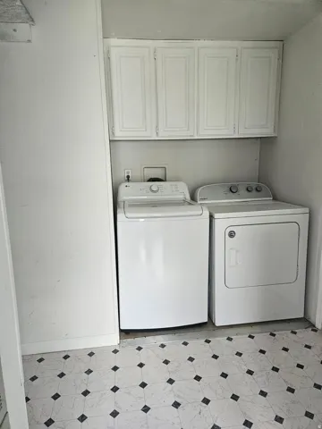 Dedicated laundry space featuring overhead white cabinetry for storage