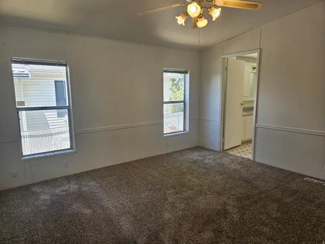 Interior room featuring two windows, neutral carpet, and white wall paneling