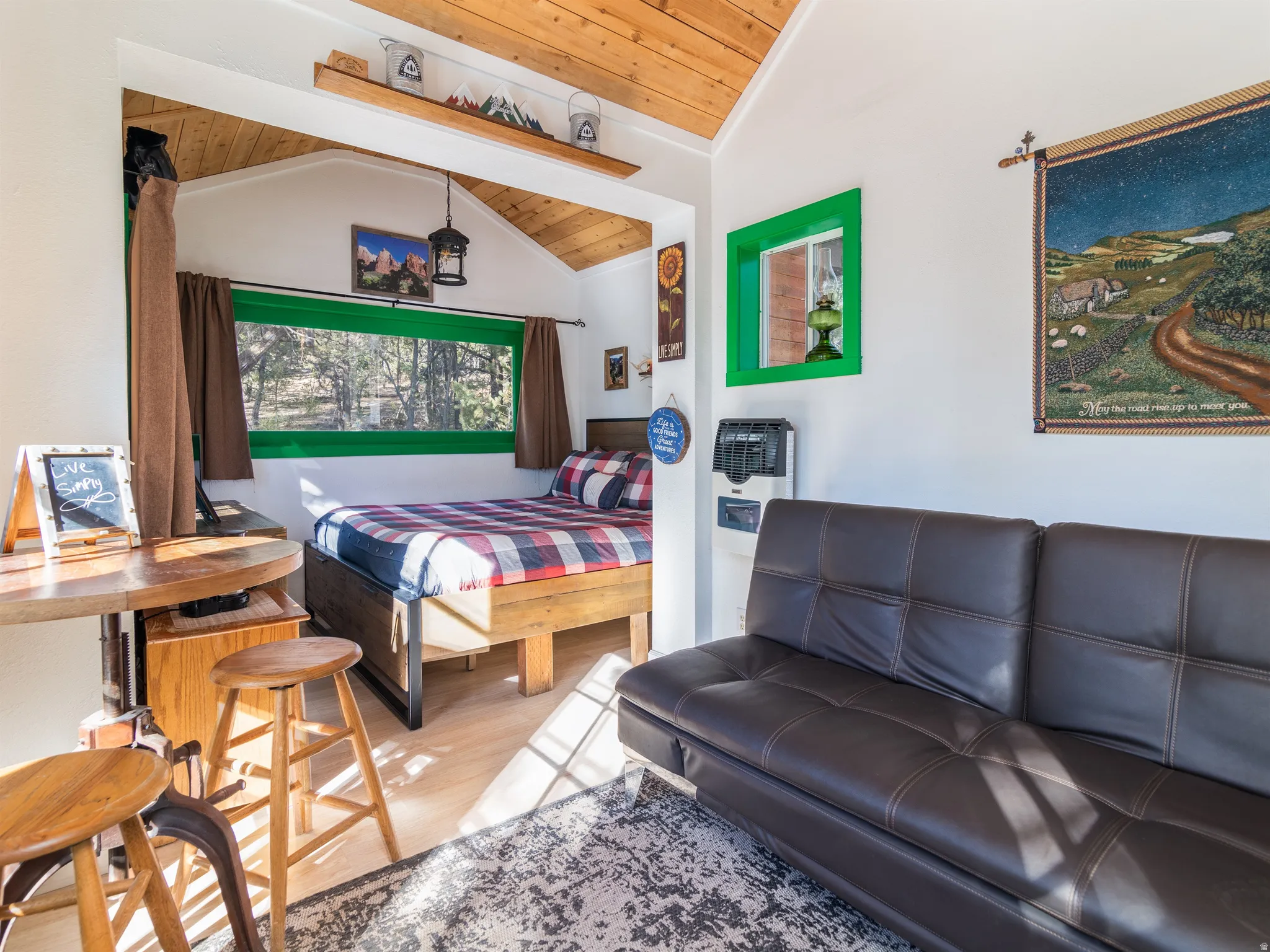 Interior featuring wood-finish flooring, a built-in sleeping area, a bright green window frame, and a wall-mounted heating unit