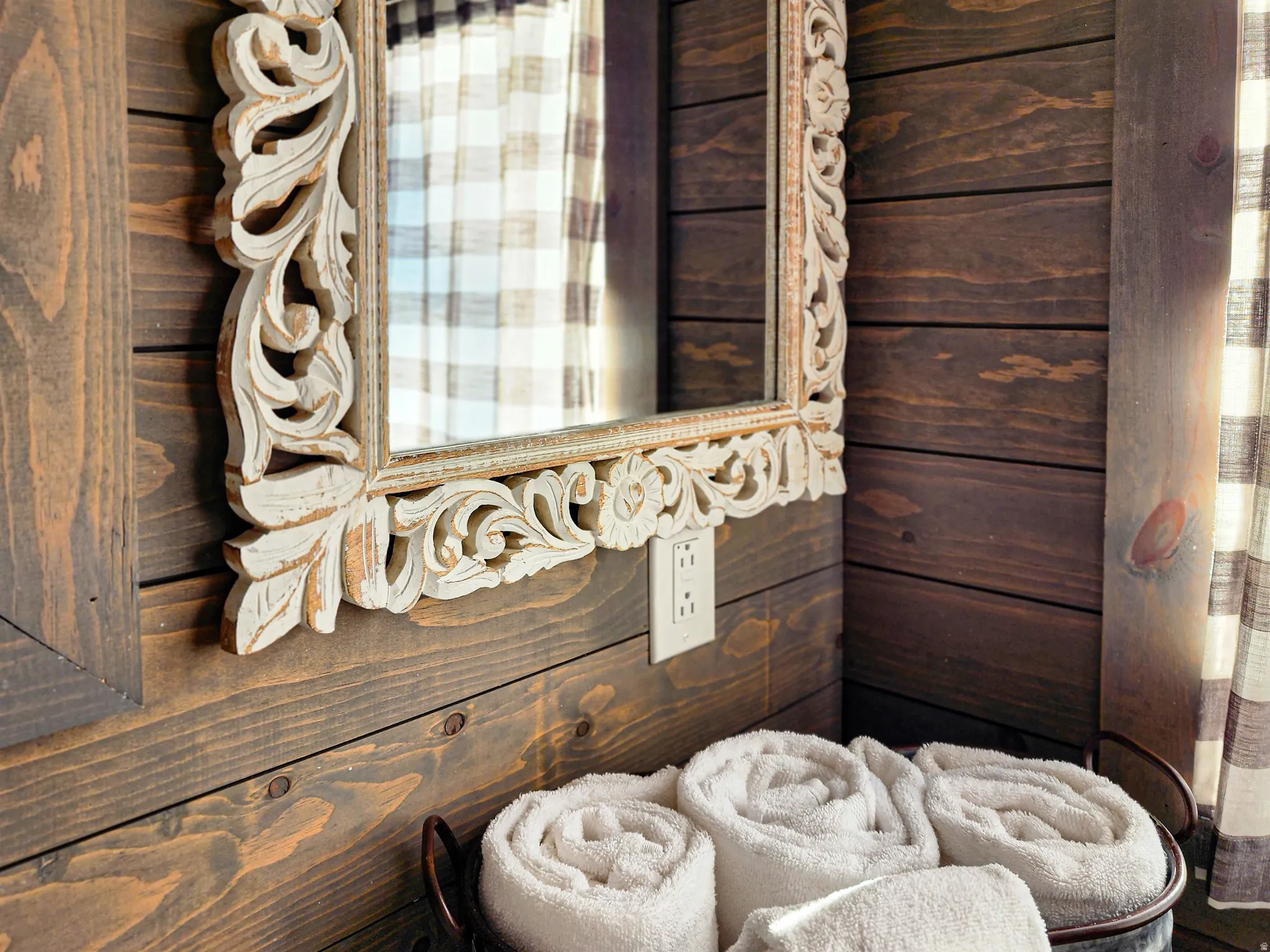 Carved wood-frame mirror with an antiqued white finish set against horizontal wood planking
