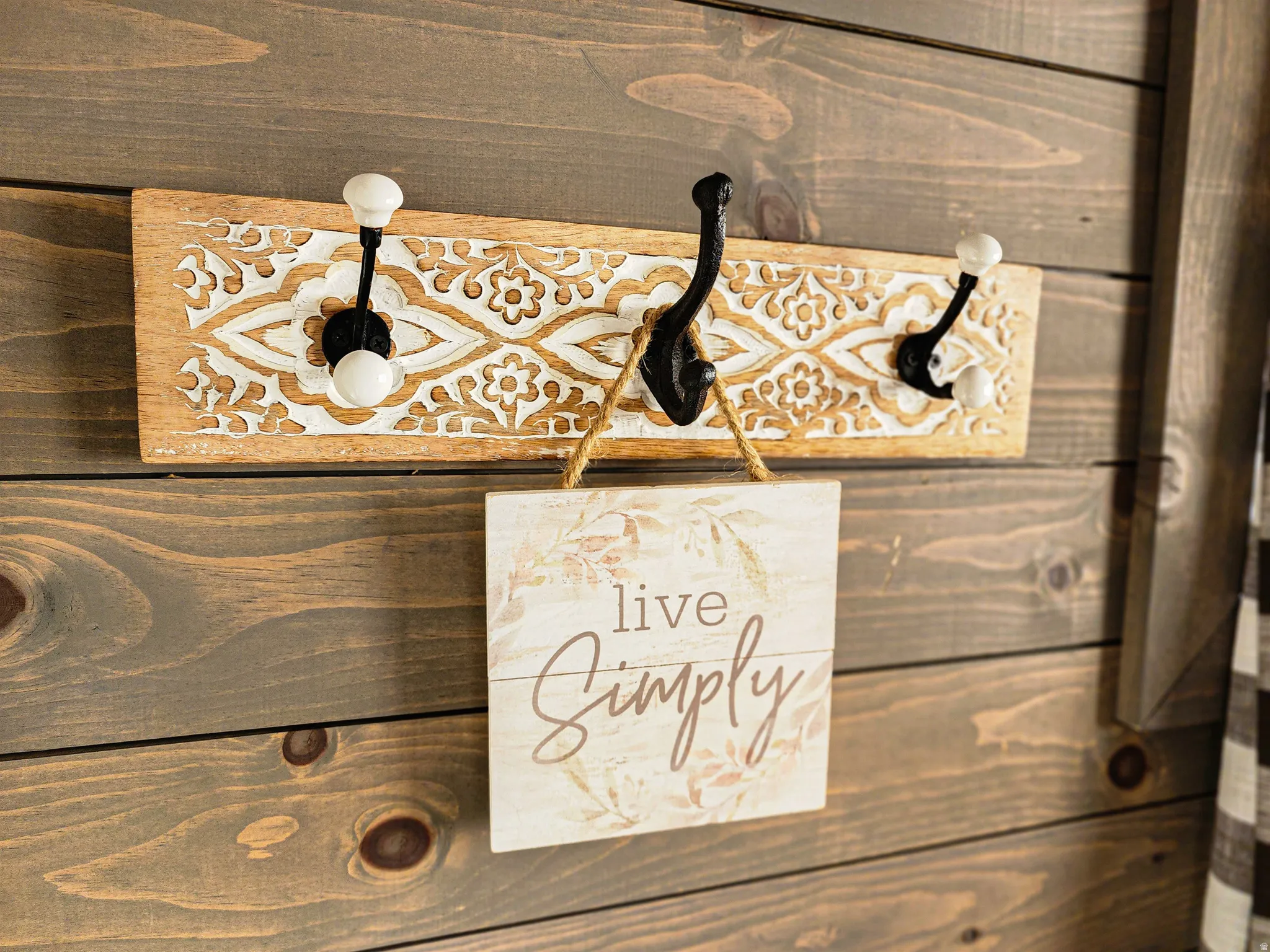 Wood-paneled wall featuring a decorative carved wood coat rack with three hooks