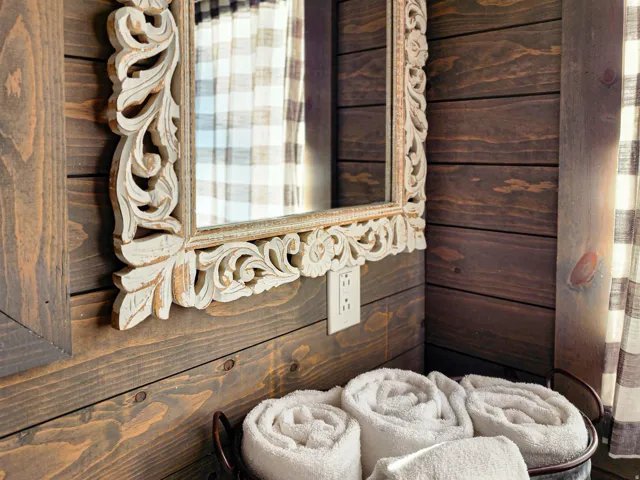 Carved wood-frame mirror with an antiqued white finish set against horizontal wood planking