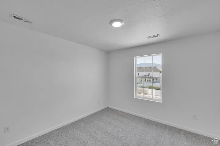 Room featuring neutral wall paint, gray carpeting, a large window with white framing, and recessed ceiling lighting