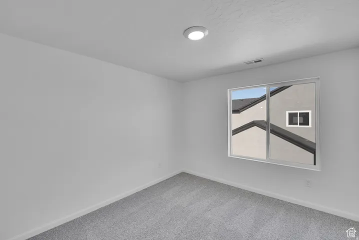 Carpeted room featuring a window with white trim, recessed lighting, and white walls