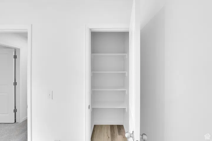 Built-in pantry shelving with white finishes and wood-finish flooring