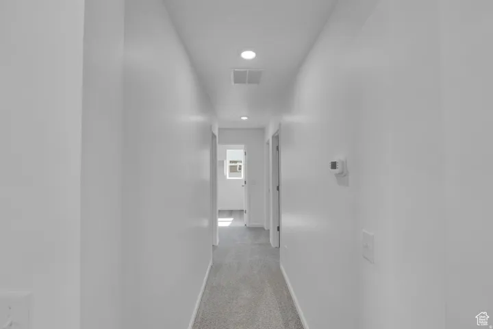 Hallway featuring light gray carpeting, recessed lighting, and white painted walls