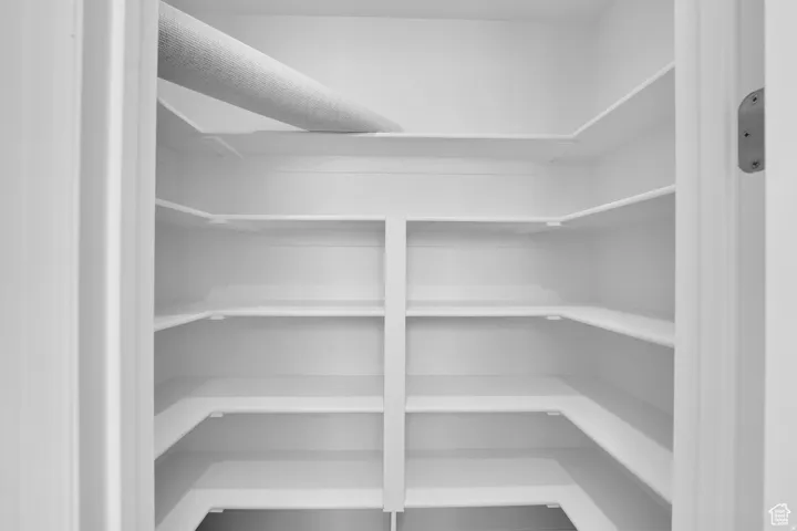 Walk-in pantry featuring multiple levels of white shelving, offering extensive storage capacity