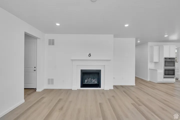 Open concept living area featuring a central fireplace with a classic white mantel