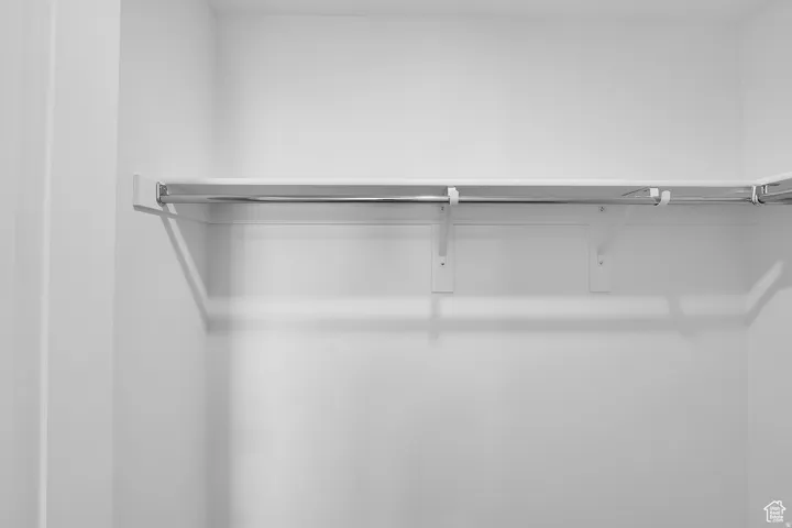 White closet with integrated shelving and chrome hanging rods