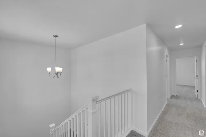 Carpeted upper-level hallway featuring a white banister and bright recessed lighting