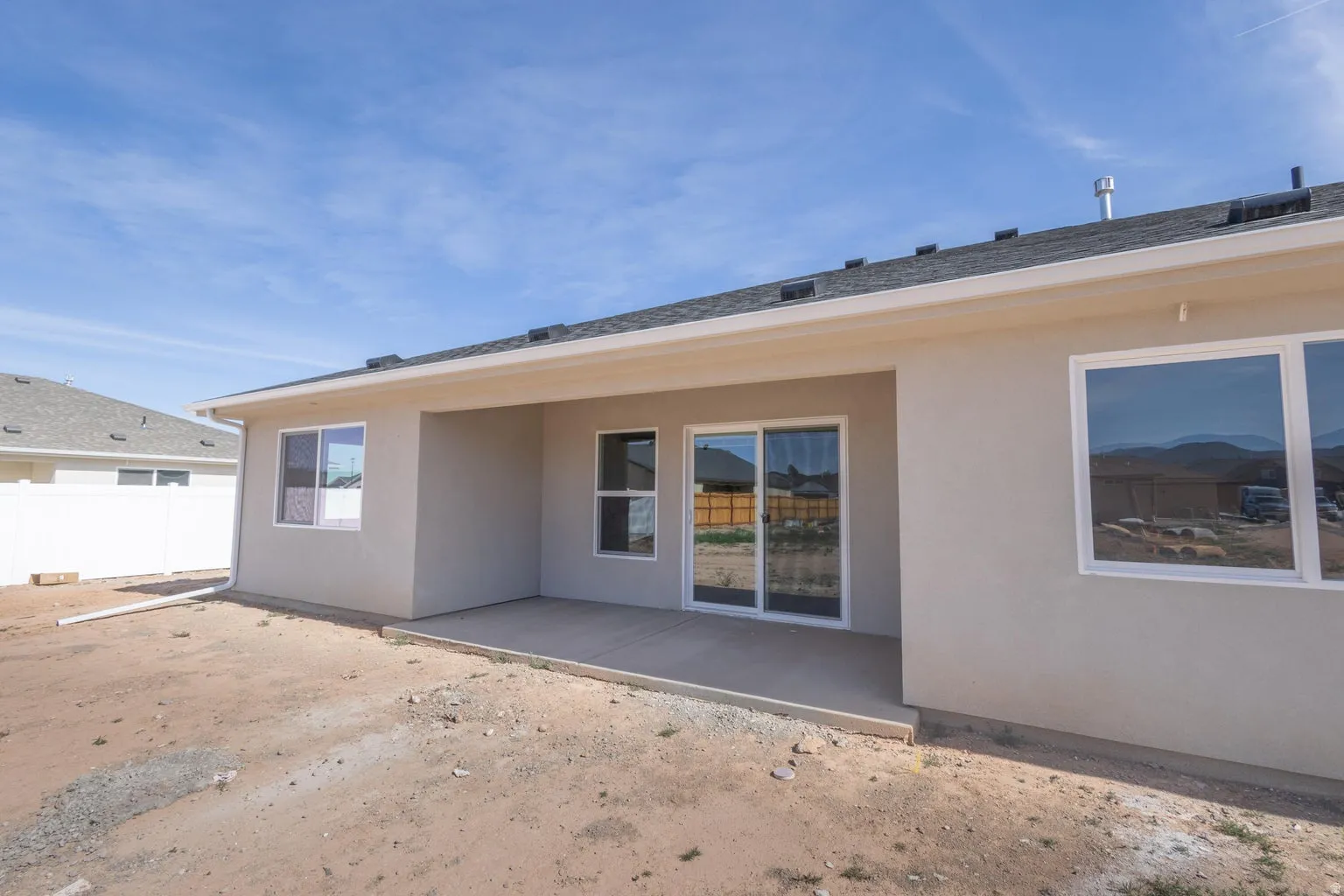 Rear exterior featuring a covered patio, sliding glass doors, white frame windows, and an asphalt shingle roof