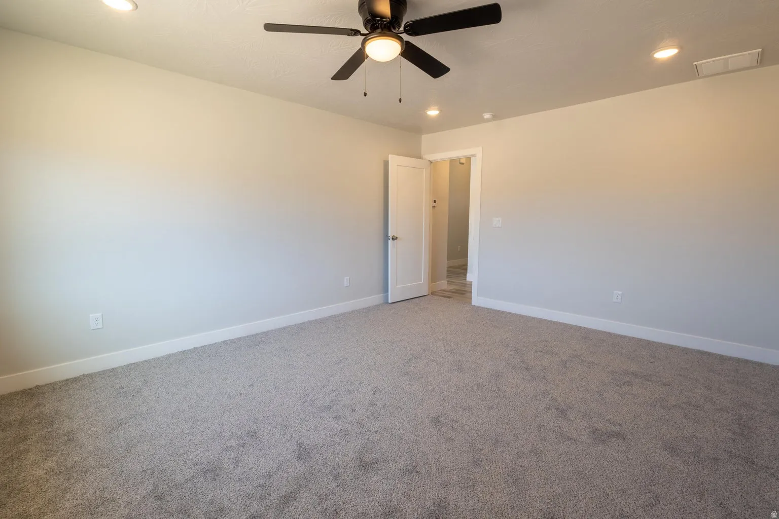 Spacious room featuring neutral carpeting, a ceiling fan with integrated lighting, and recessed ceiling lights