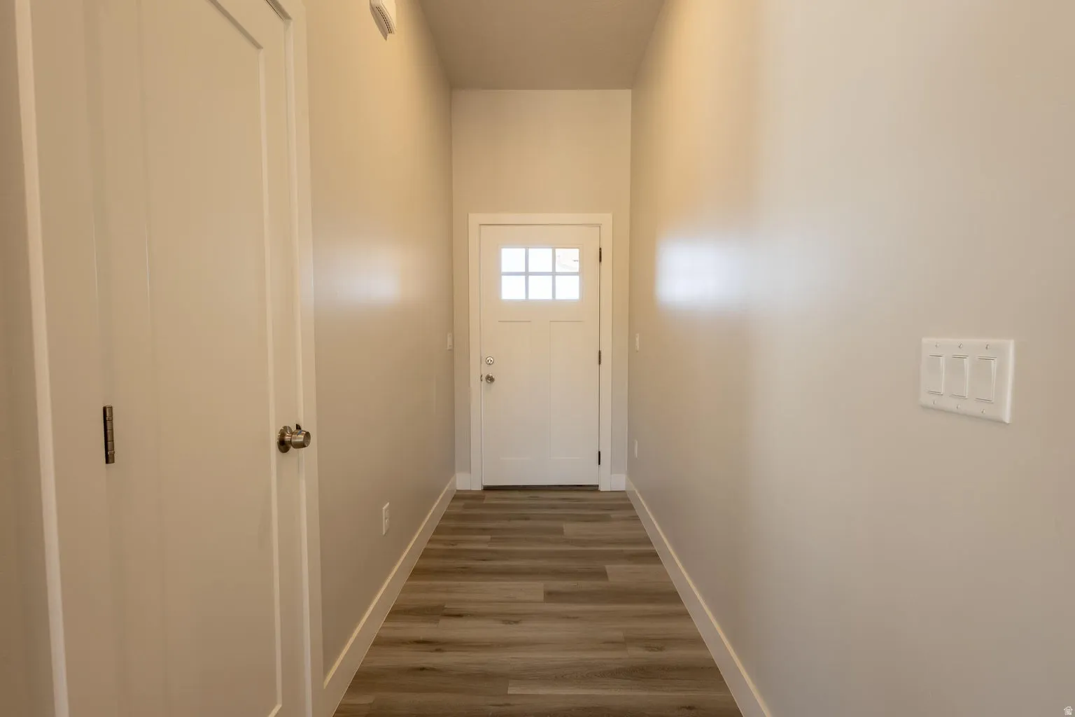 Entryway featuring light wood-finish flooring, neutral wall paint, and a bright white door with multiple glass panes