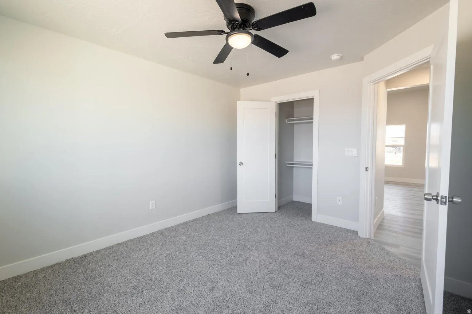 Interior room featuring light grey walls, grey carpeting, and white trim