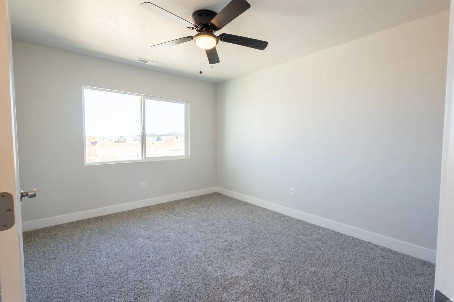 Room featuring neutral-toned carpeting, white baseboards, and a modern ceiling fan with integrated lighting