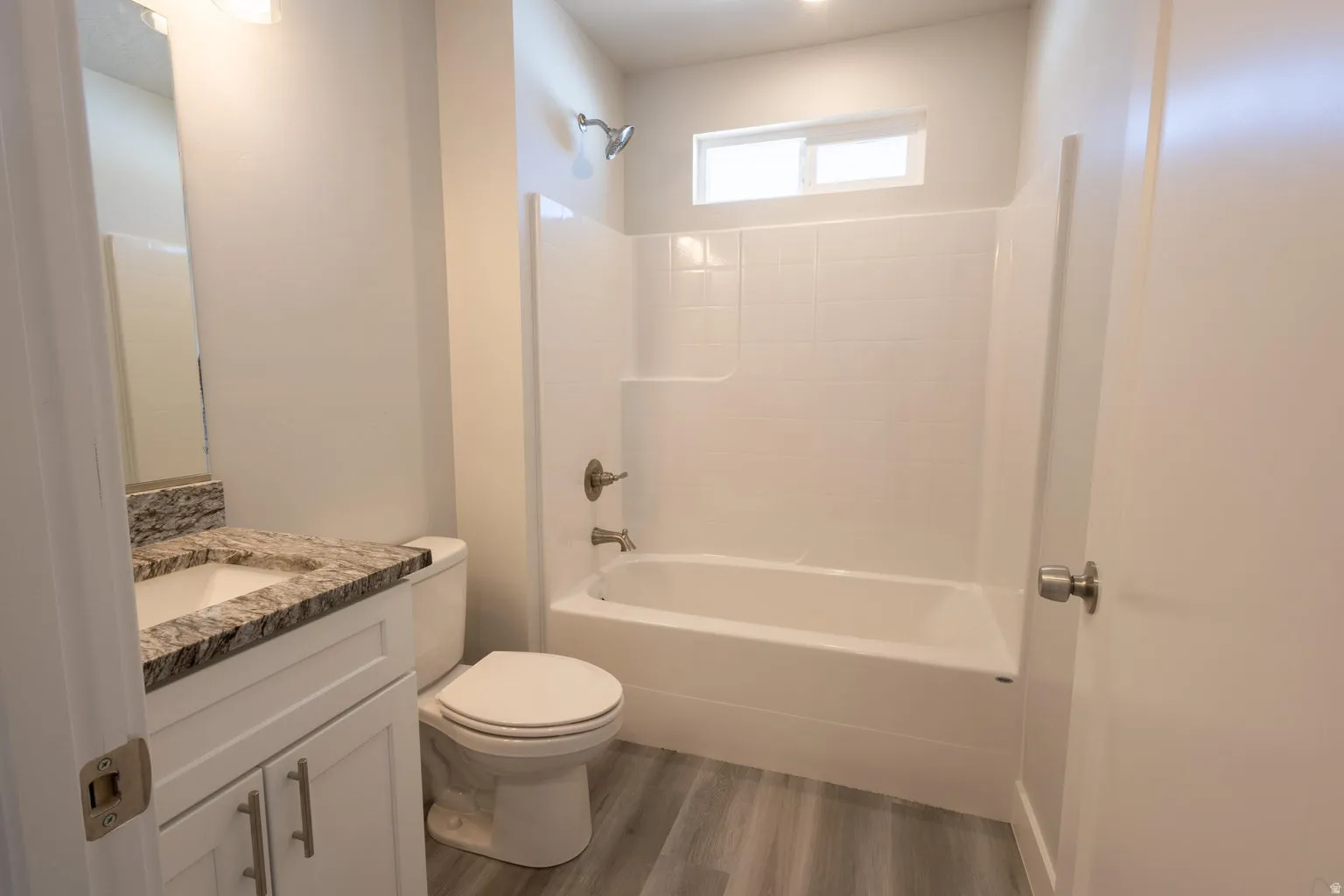 Bathroom featuring a white vanity with granite-style countertop, undermount sink, and brushed nickel hardware
