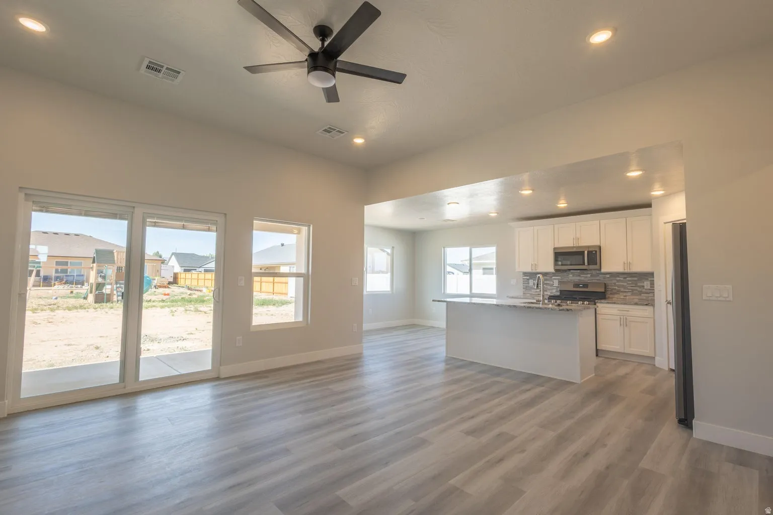 Expansive interior showcasing light wood-finish flooring, recessed lighting, and a modern ceiling fan