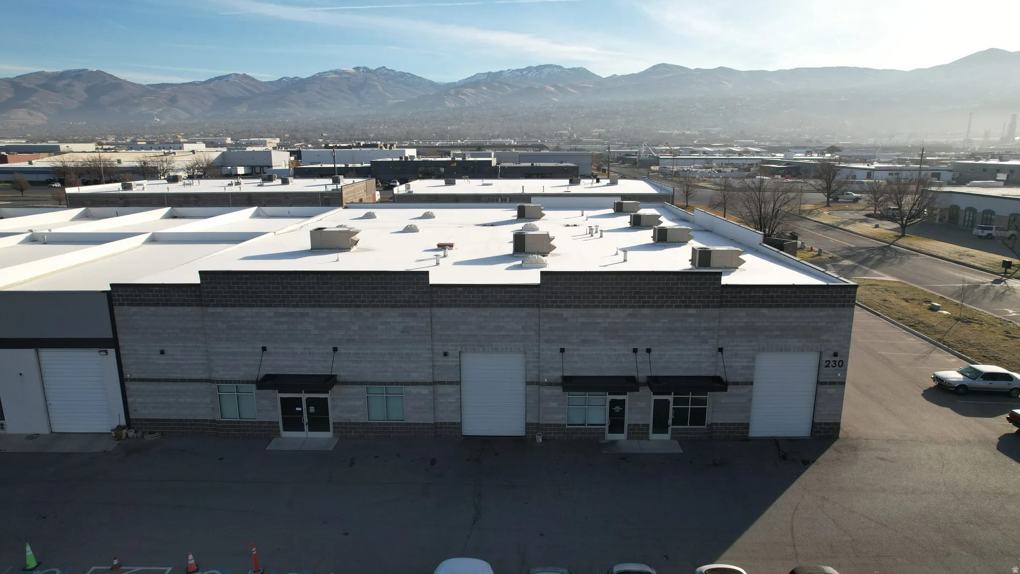 Commercial building featuring a flat roof, three roll-up doors, multiple entryways with awnings, and a partially brick facade