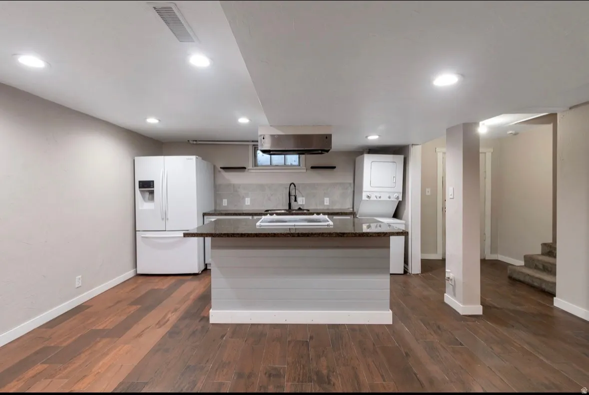 Open-concept living space featuring wood-finish flooring, recessed lighting, and a kitchen island with integrated cooktop