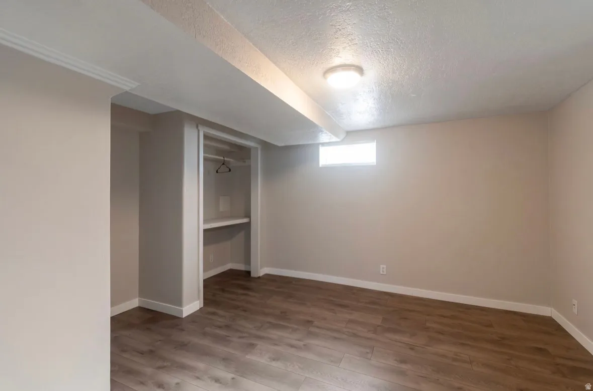 Spacious room featuring wood-finish flooring, neutral wall paint, and white trim