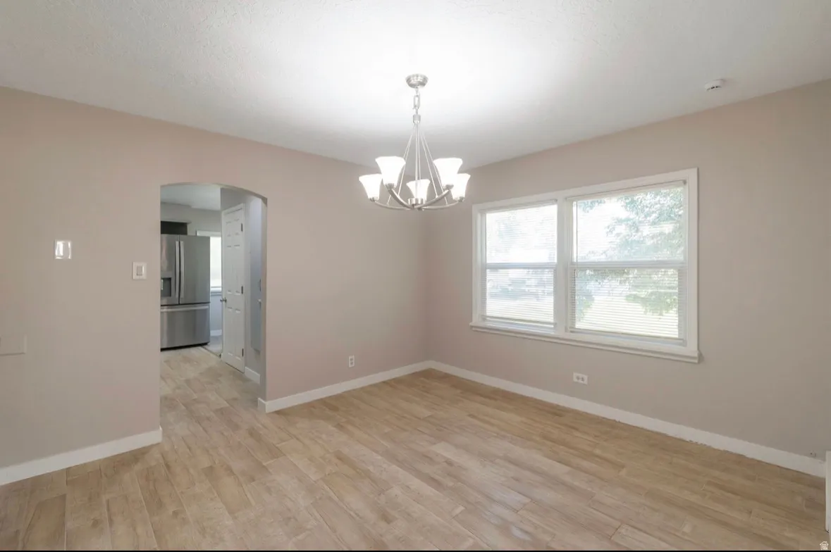 Dining area featuring wood-finish flooring, a contemporary chandelier, and a large window