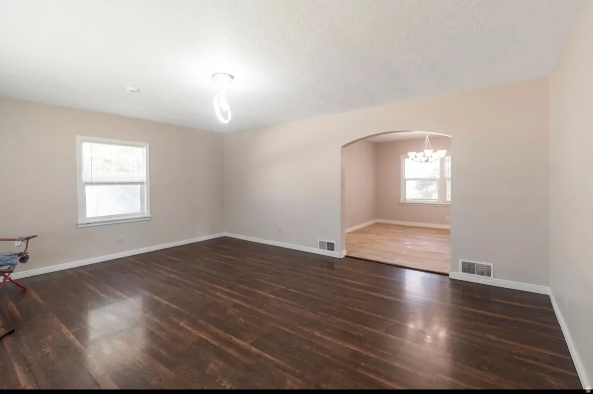 Living area featuring dark wood-finish flooring, light-colored walls, and a large window with white blinds
