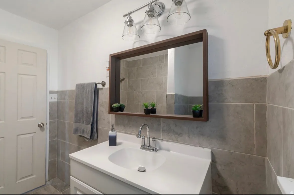 Vanity with integrated sink, chrome faucet, and rectangular mirror with a wood-finish frame