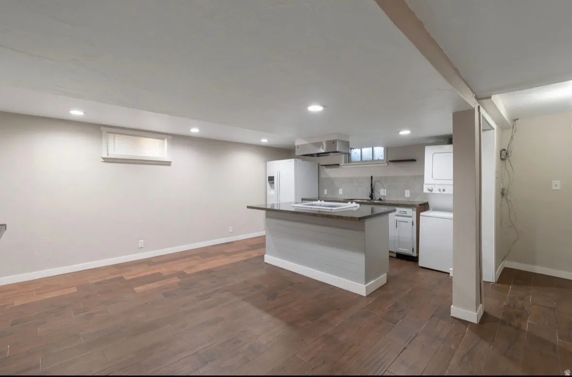 Open-concept living area featuring wood-finish flooring, recessed lighting, and a kitchen island with a stone countertop