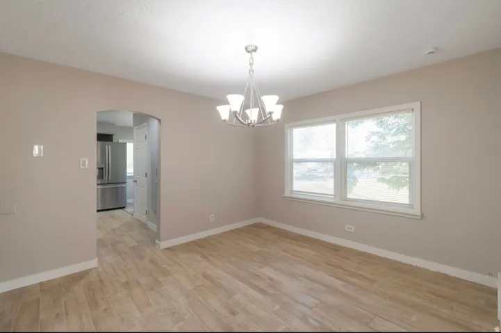 Dining area featuring wood-finish flooring, a contemporary chandelier, and a large window