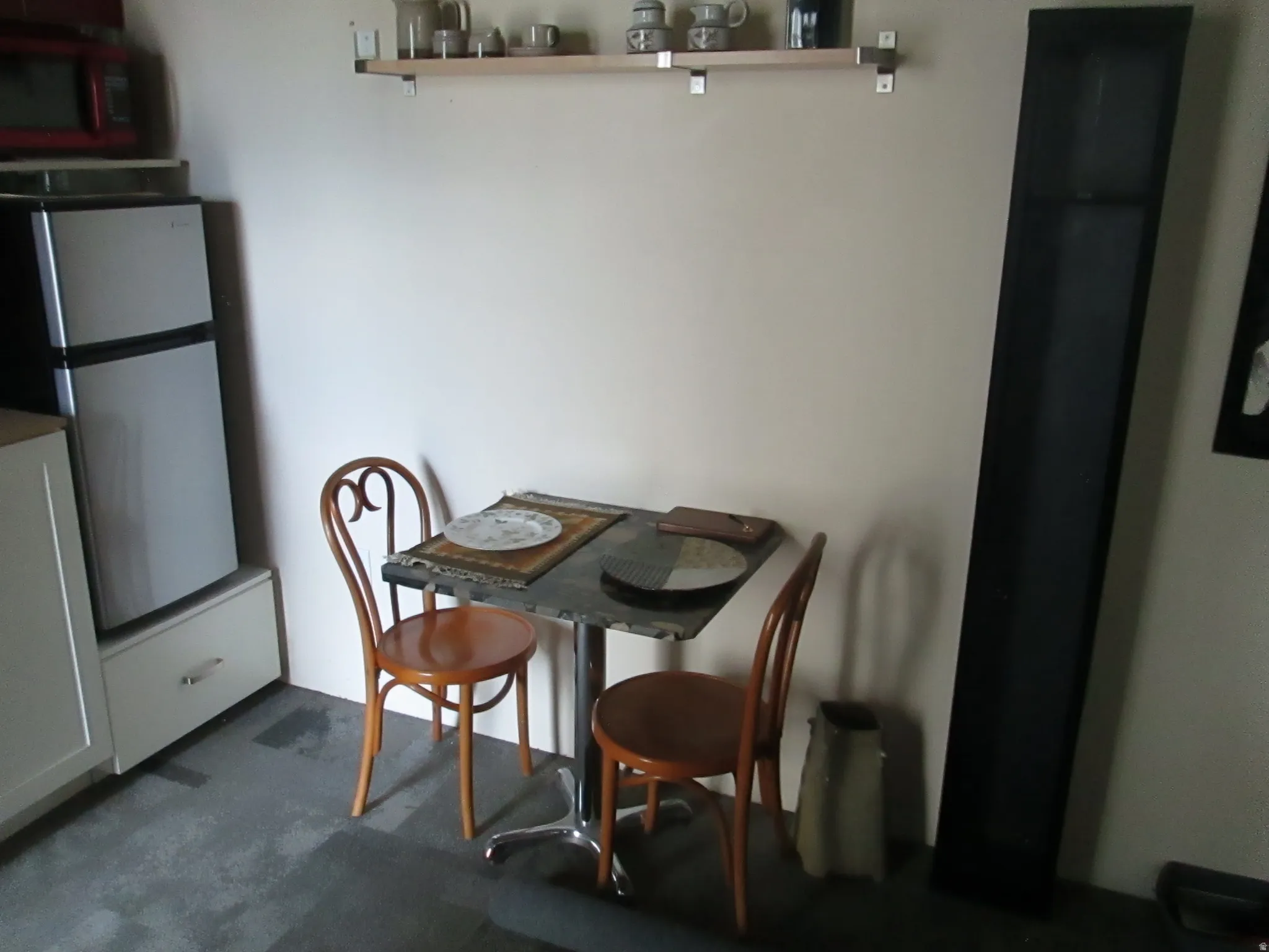 Compact kitchen area featuring a built-in shelf, light-toned cabinetry, and a neutral wall color