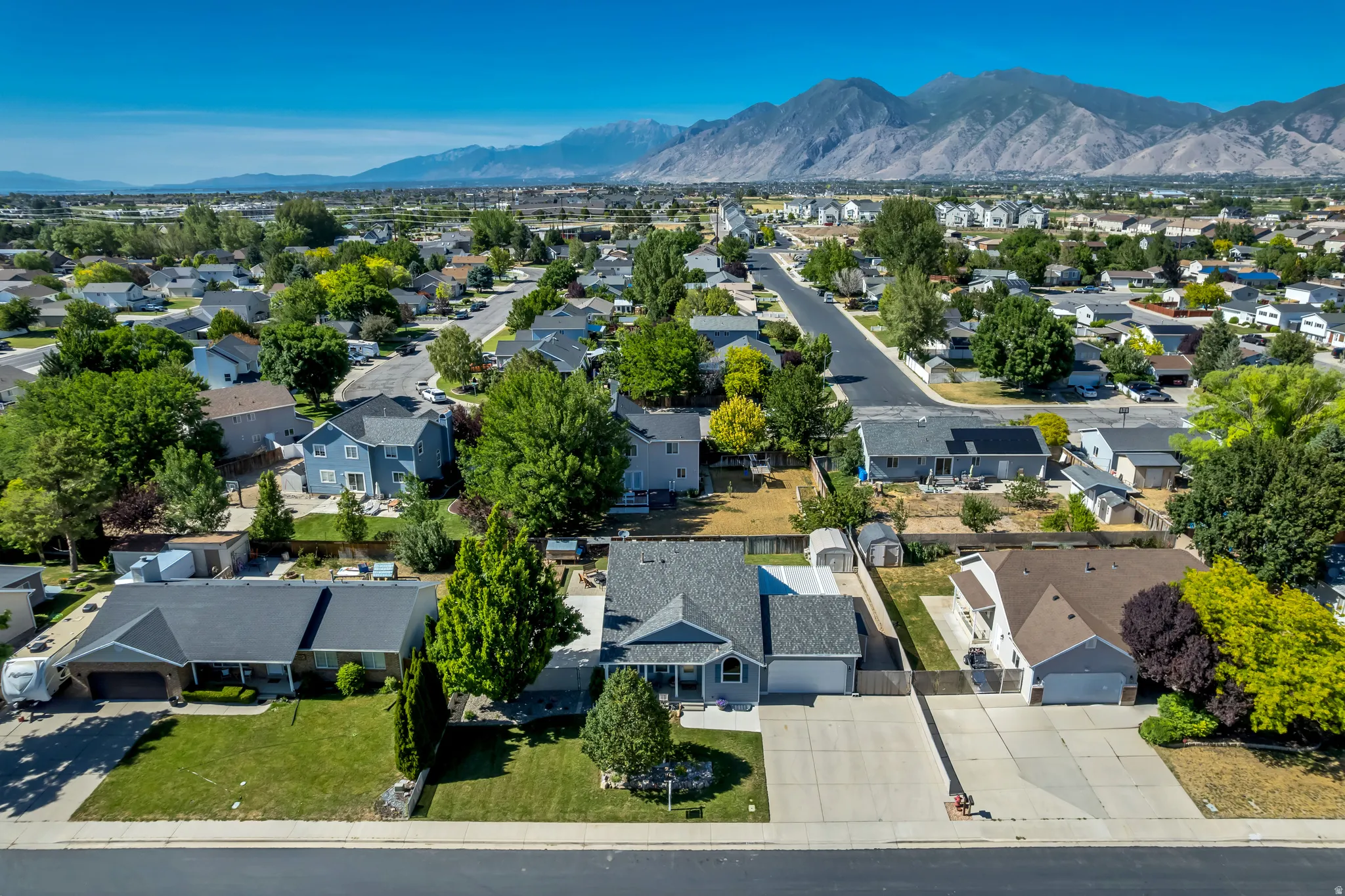 Expansive suburban neighborhood featuring a residential street, mature trees, and mountainous terrain