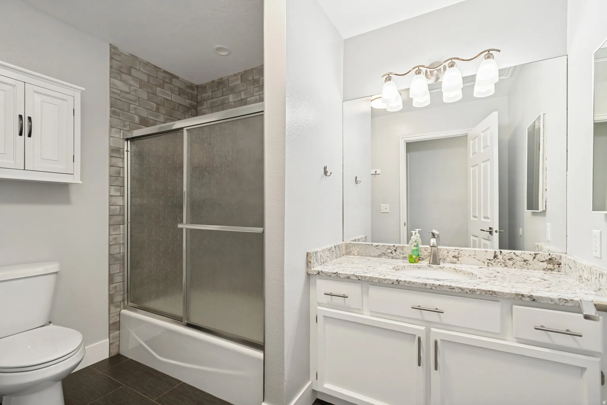 Bathroom featuring a vanity with a light-toned countertop, white cabinetry, and a large mirror