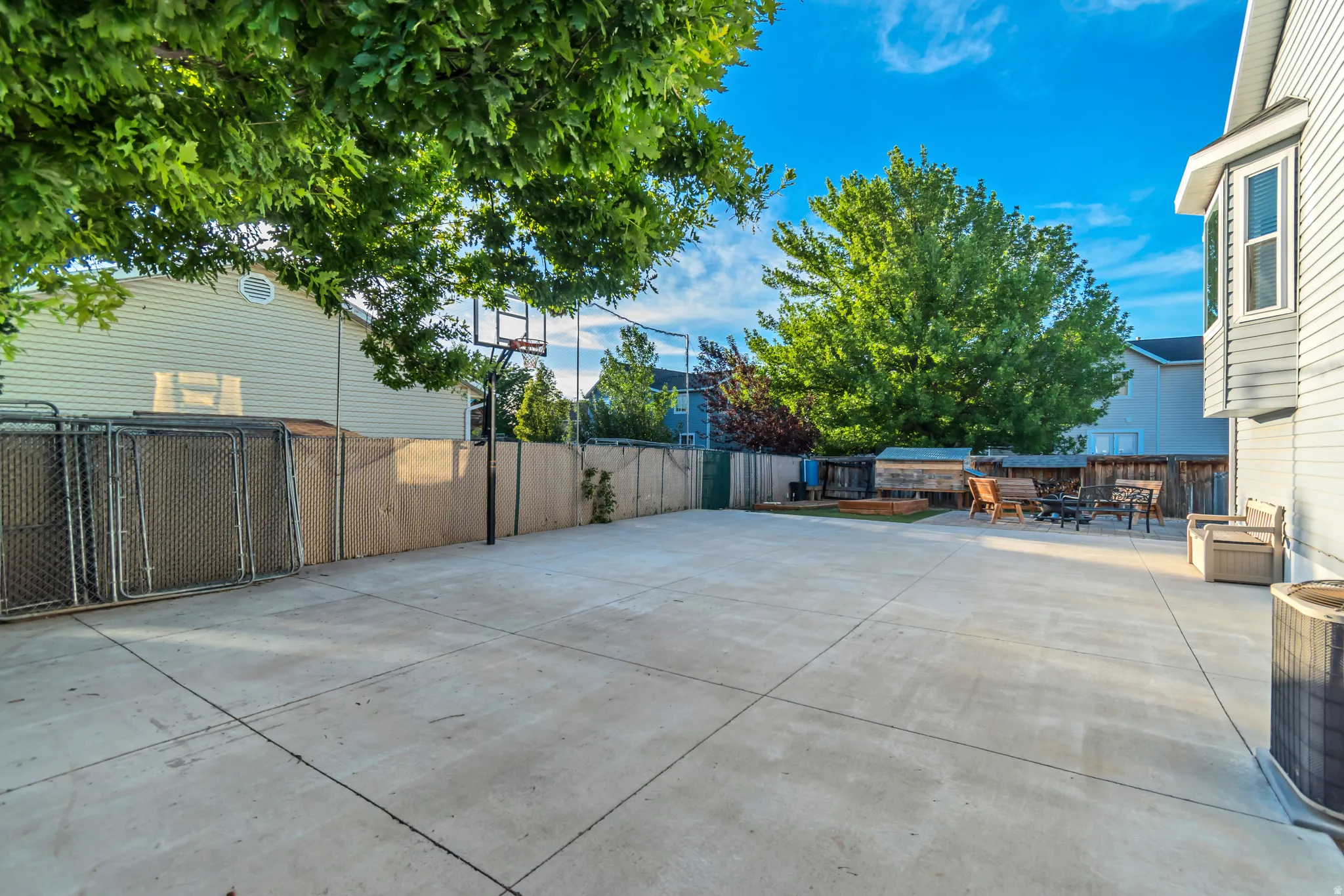 Expansive concrete patio area featuring a basketball hoop