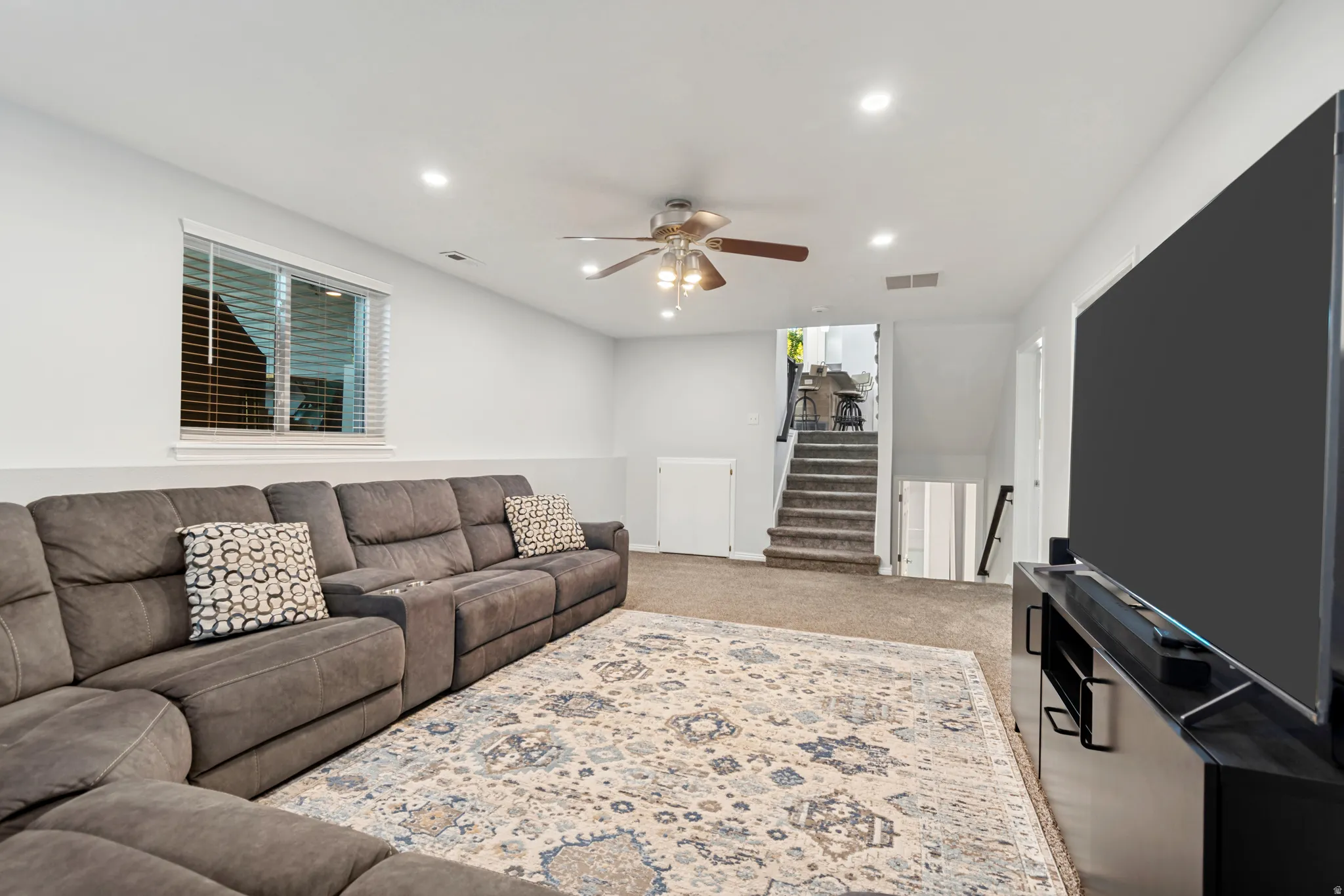 Carpeted lower level featuring recessed lighting, a ceiling fan, and painted walls with wainscoting