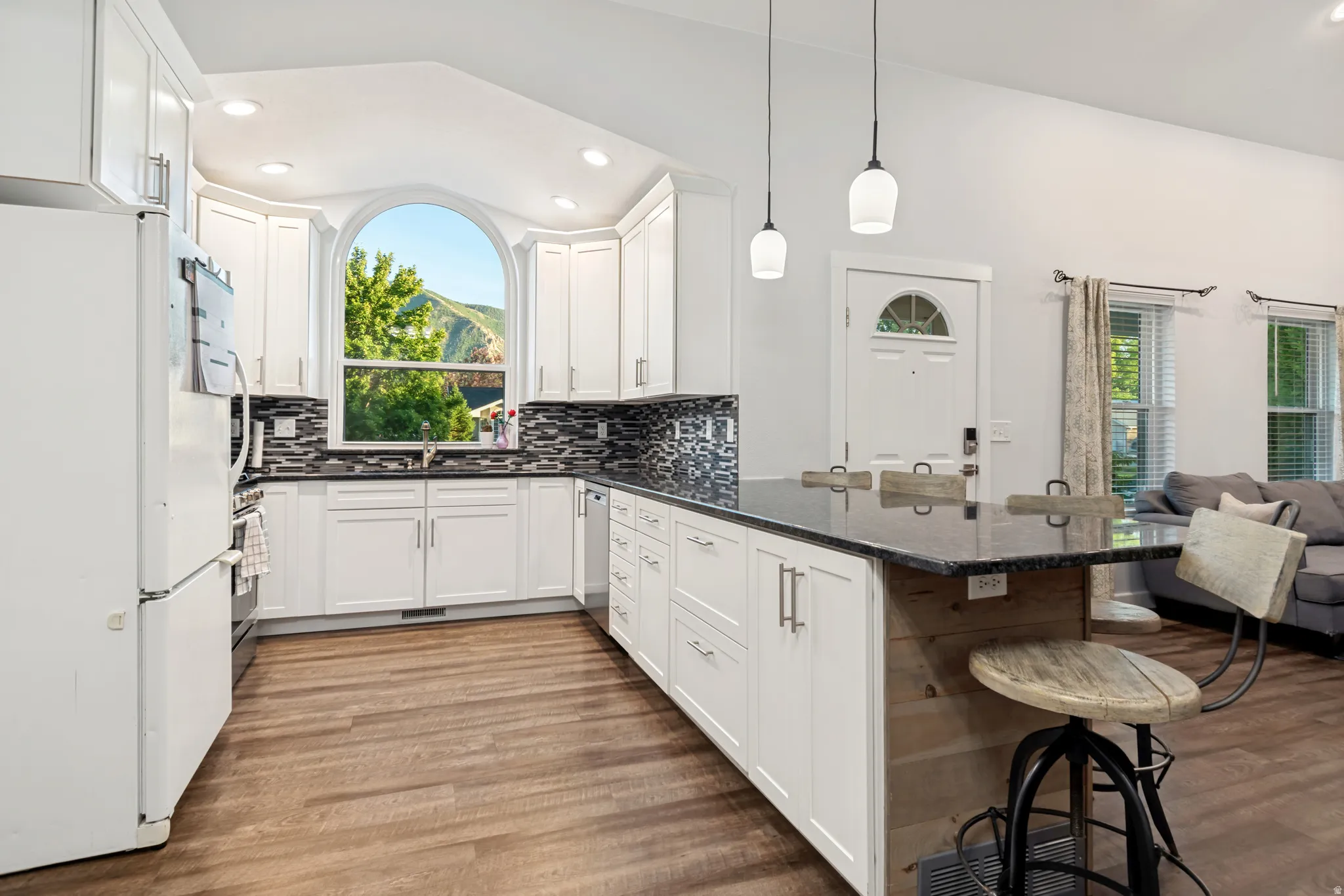 Bright kitchen featuring white cabinetry, dark countertops, and a mosaic tile backsplash