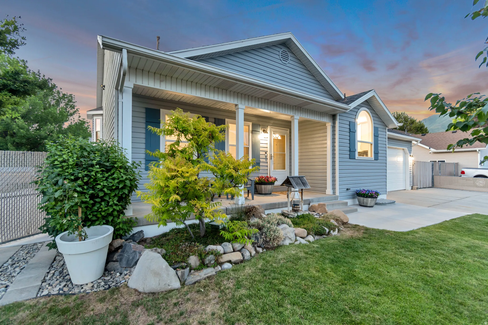 Welcoming front exterior featuring light blue siding, a covered porch with white columns, and a landscaped rock garden