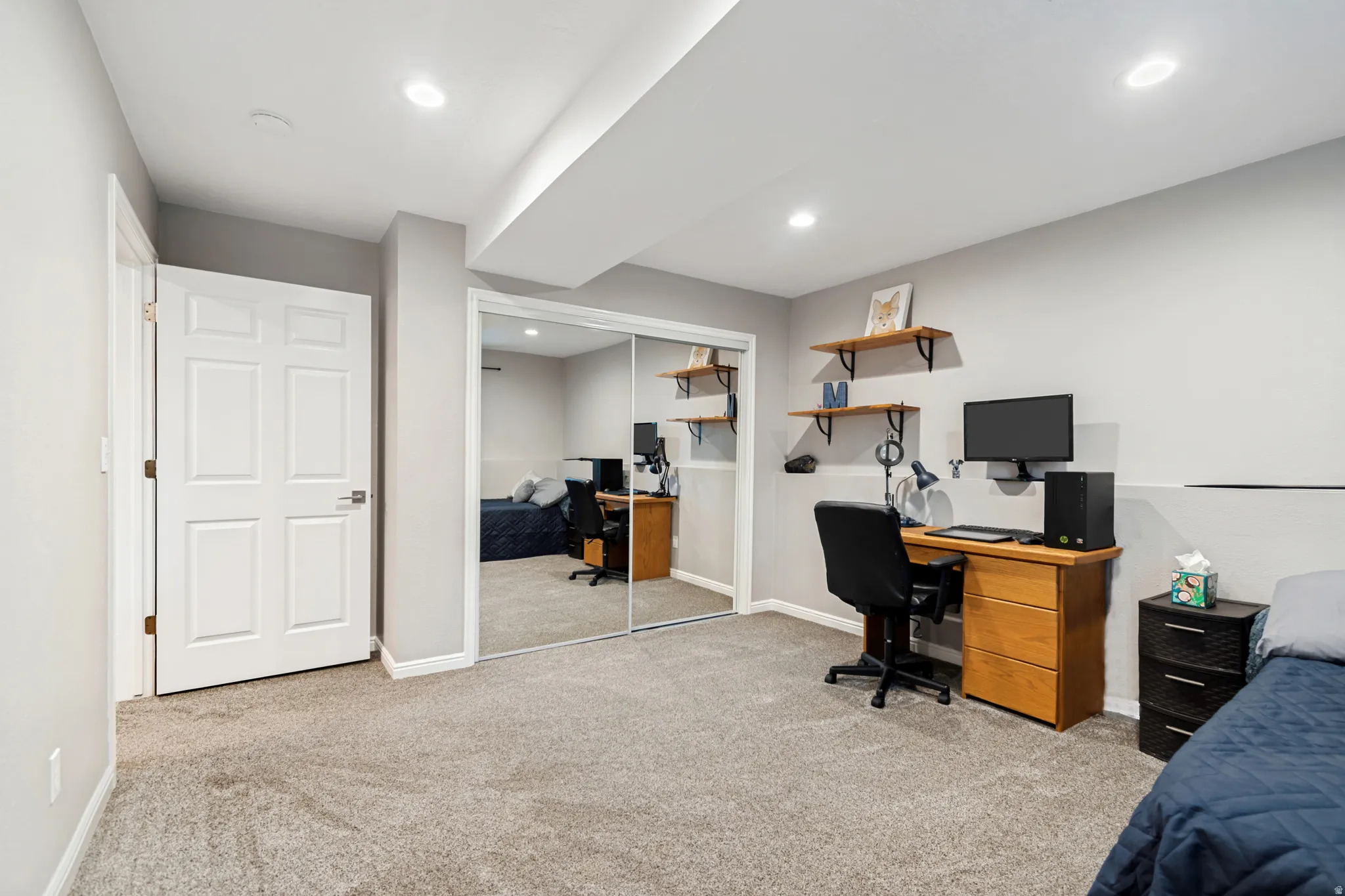 Carpeted room featuring a white paneled door, mirrored closet doors, recessed lighting, and wall-mounted shelving