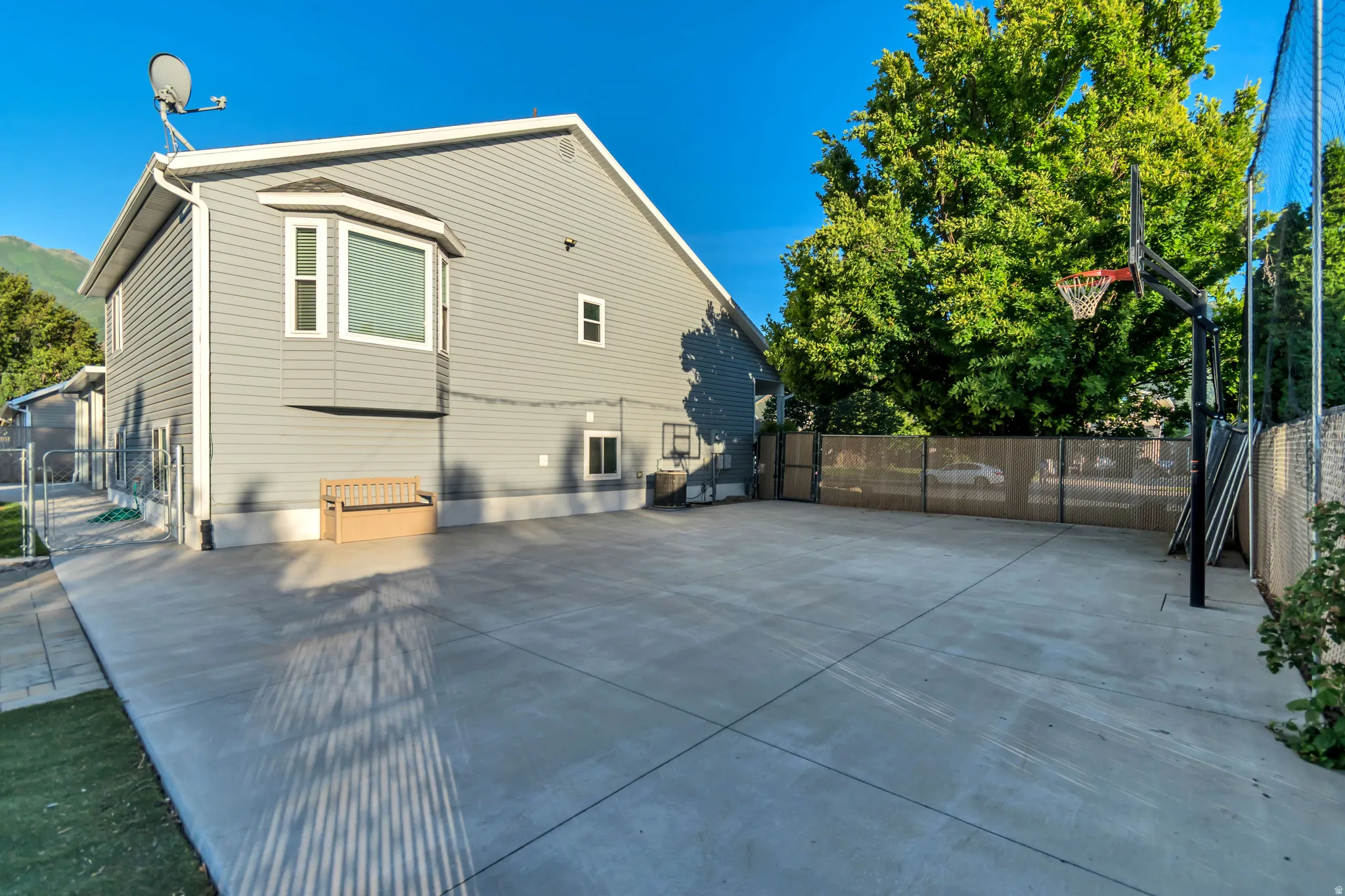 Expansive concrete hardscaping with a basketball hoop and perimeter fencing