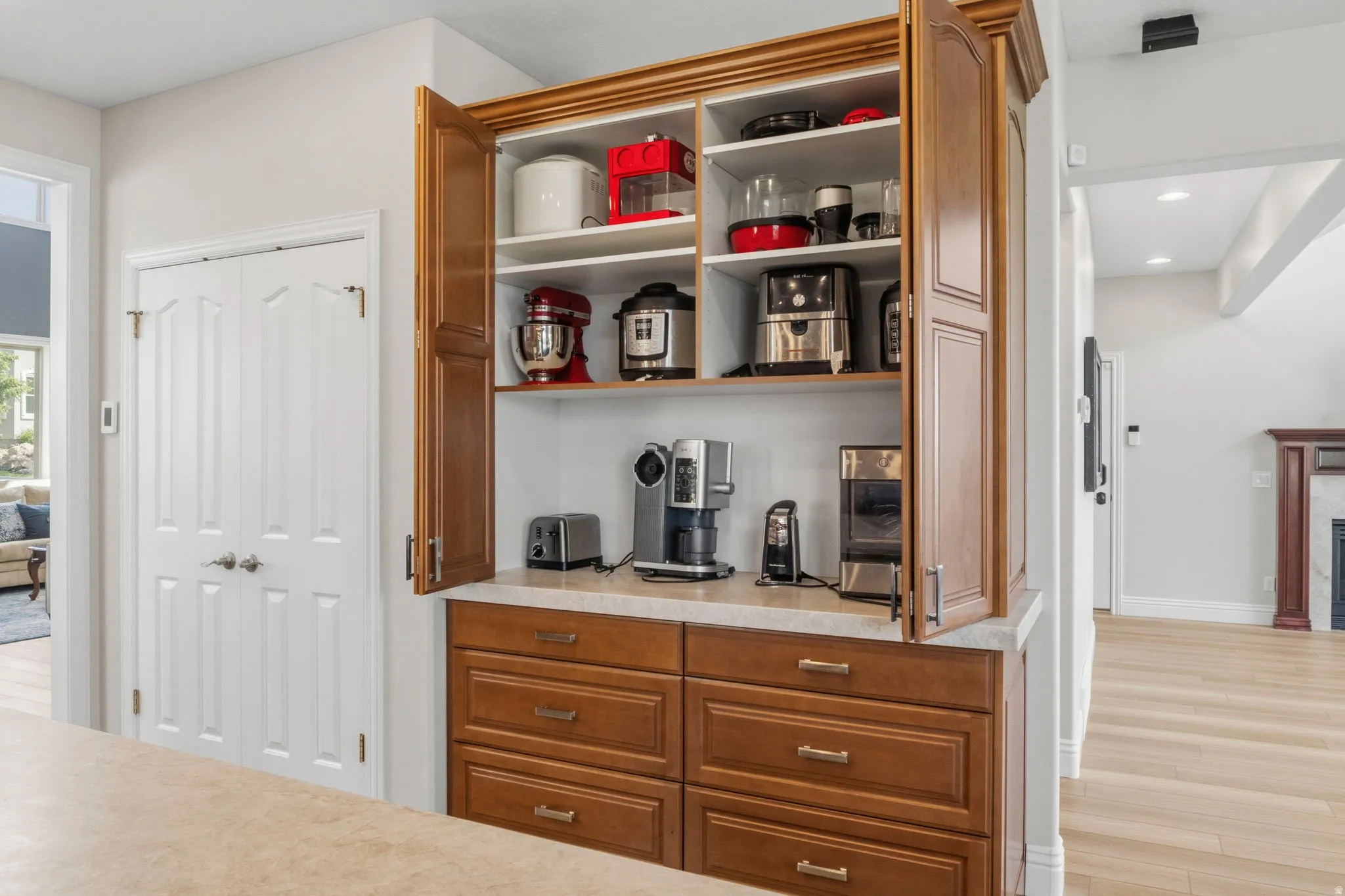 Built-in kitchen cabinetry with a light wood-finish, featuring multiple shelves and a countertop workspace