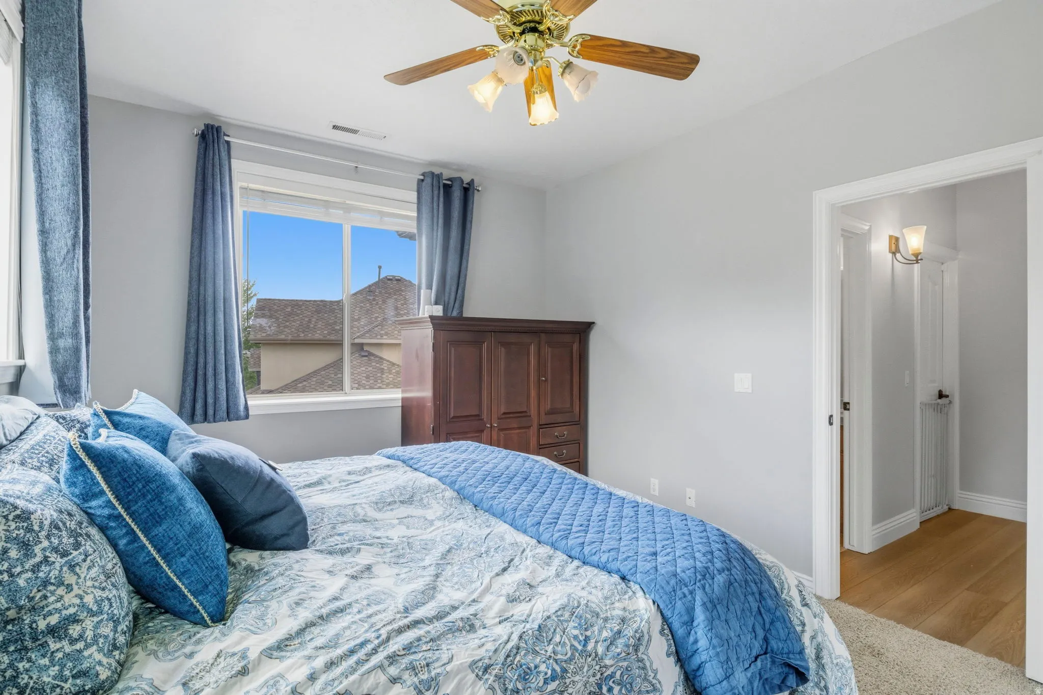 Bedroom with neutral wall tones, a ceiling fan with integrated lighting, and a large window offering exterior views