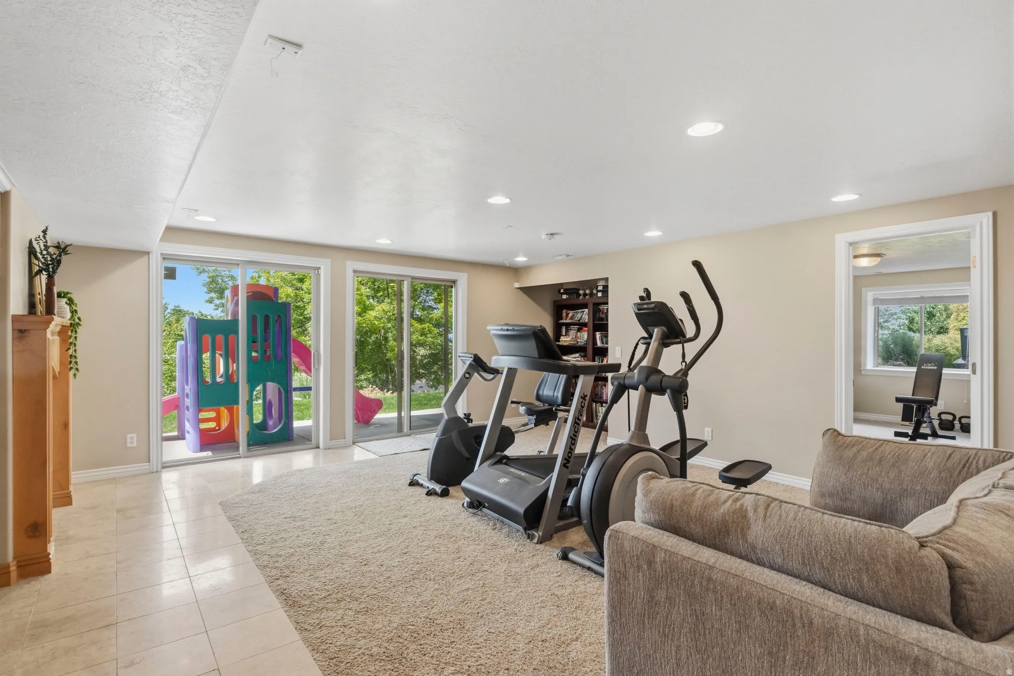 Expansive lower-level space with dual sliding glass doors, recessed lighting, and a built-in bookshelf