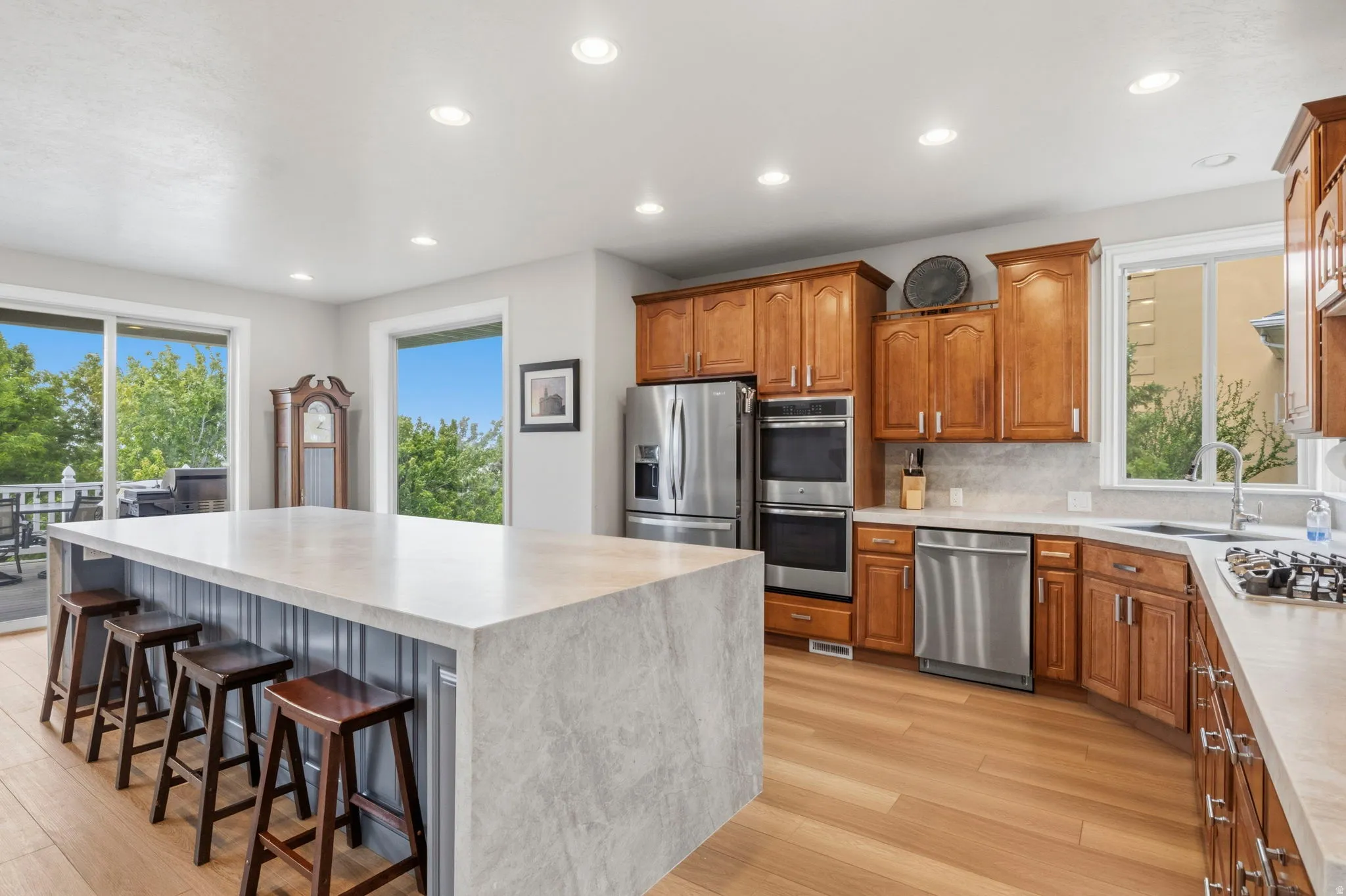 Kitchen featuring a large central island with seating, wood-finish flooring, stainless steel appliances, and wood cabinetry